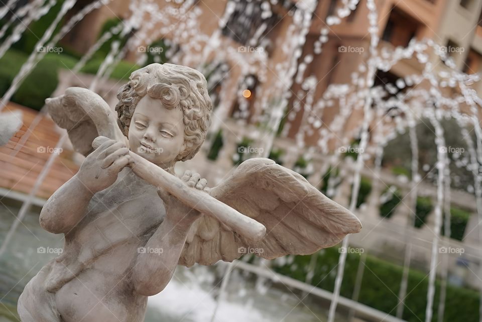 A statue of Cupid playing a flute in the middle of a fountain
