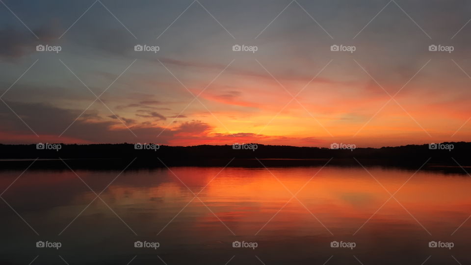 Bright red glow of the sun rising over the water