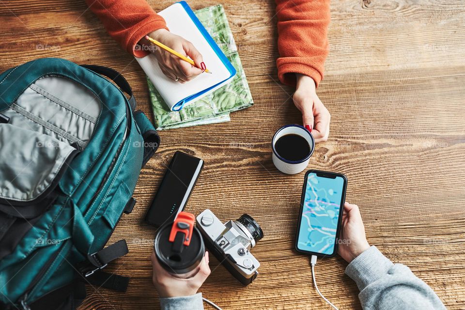 Family planning vacation trip. Girl searching travel destination and routes using navigation map on mobile phone. Woman writing journal and making notes. Charging smartphone with power bank. Using technology while travelling