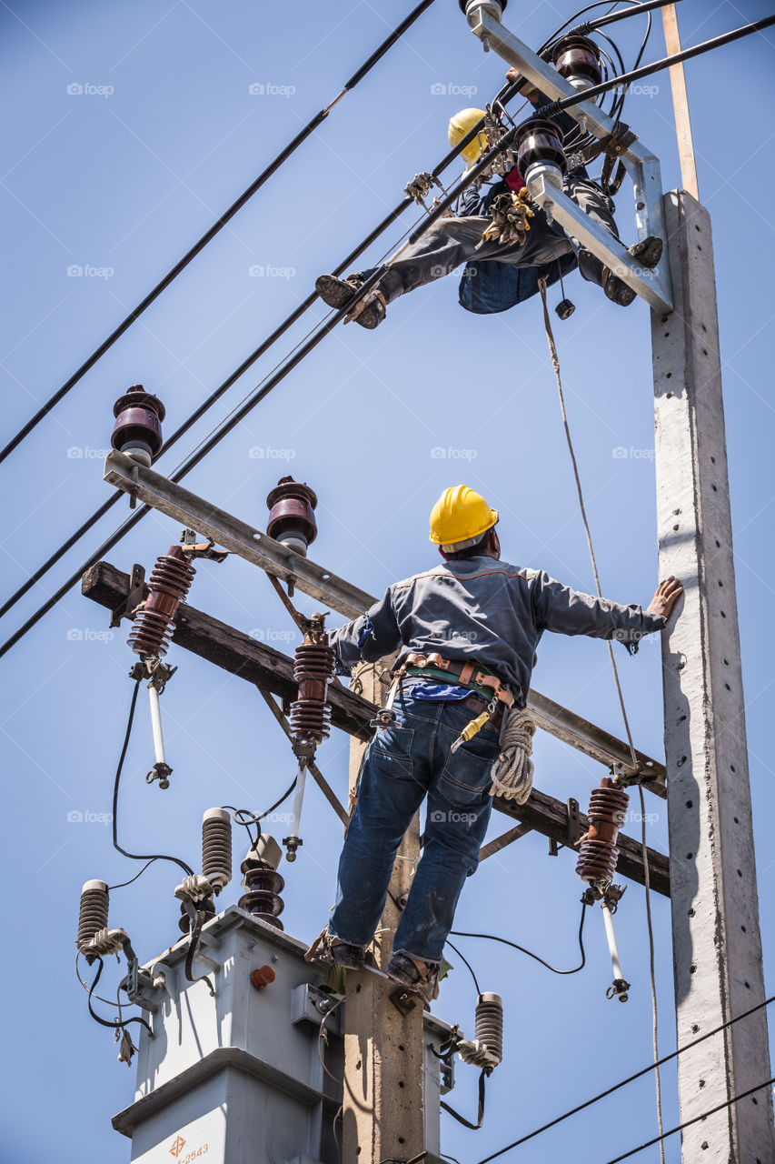 Electrician working together on the electricity pole to replace the electrical insulator