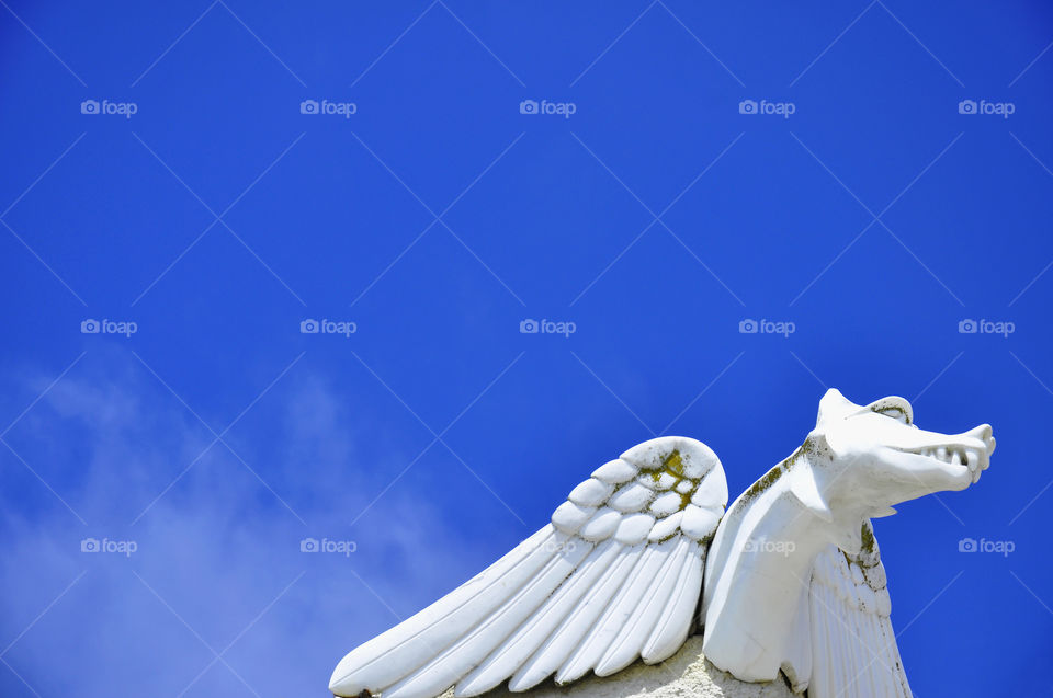 Gargoyle against a bright blue sky.