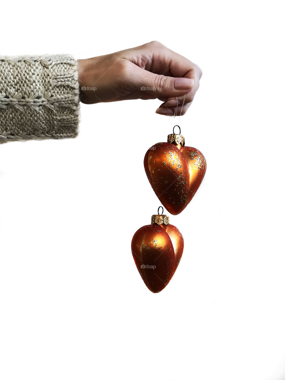 Two heart shaped Christmas decorations in hand 