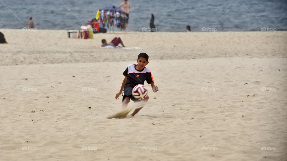 Boy playing football at beach