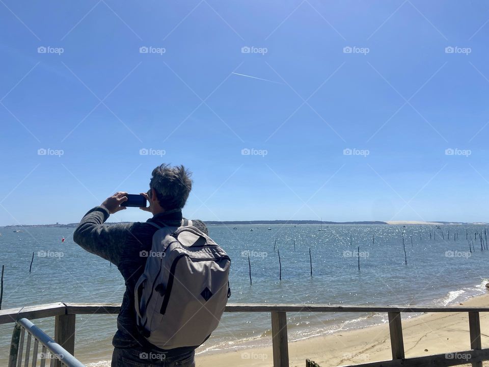 Rear view of man taking photo of the sea