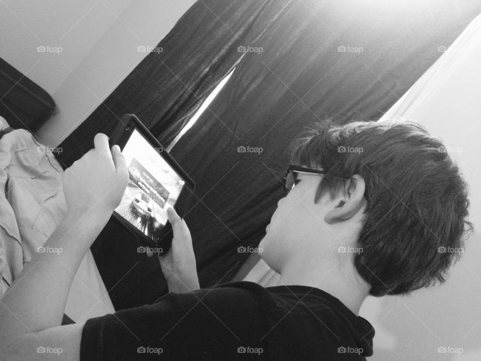 Preteen boy playing a racing game on his iPad 