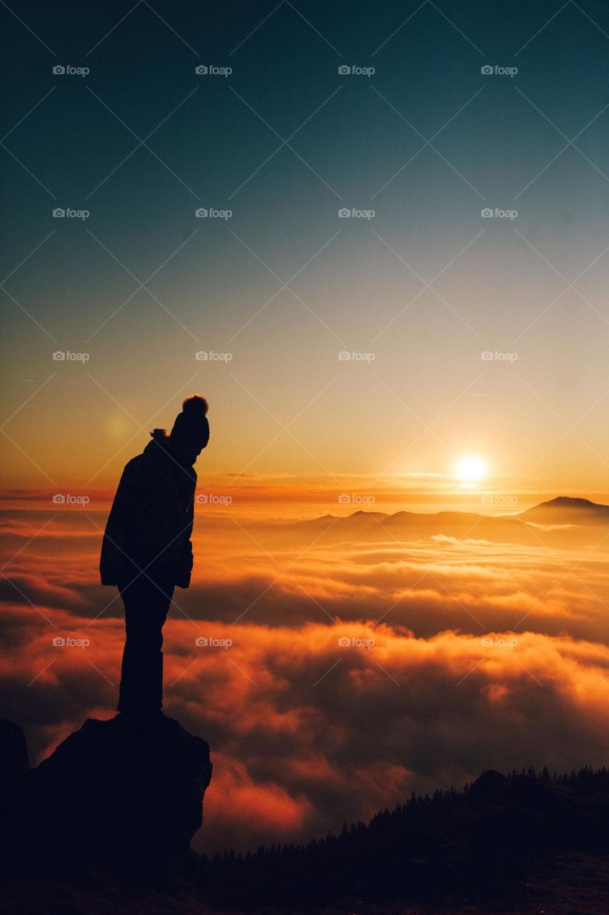 woman sitting above the clouds at sunset