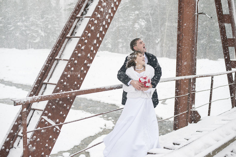 Loving couple posing on railway bridge during winter