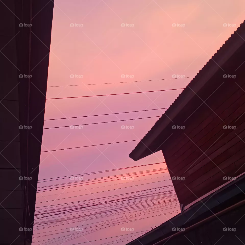 "An evening with a warm pink sky, peacefully framed between two houses."