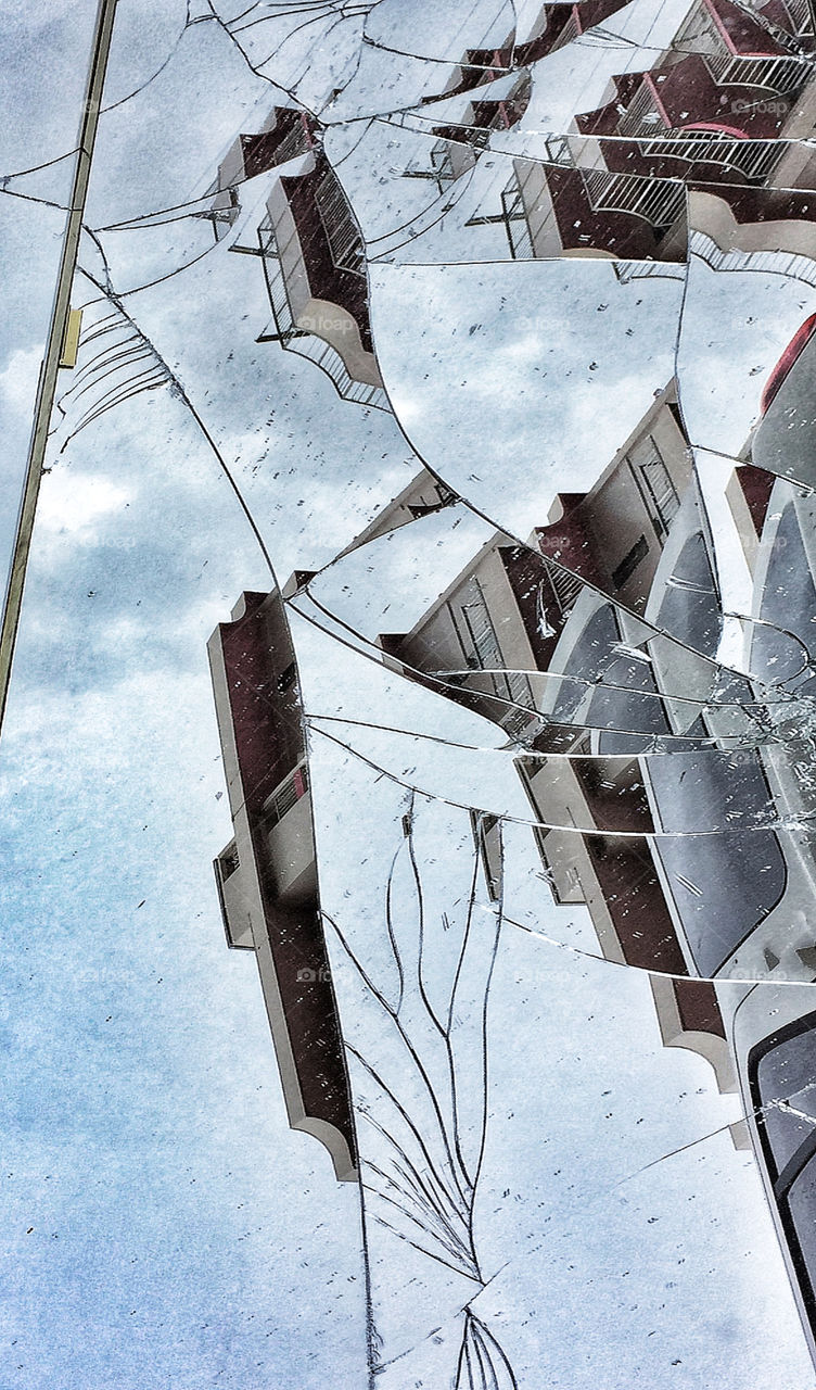 Buildings and sky reflected in a shattered mirror 
