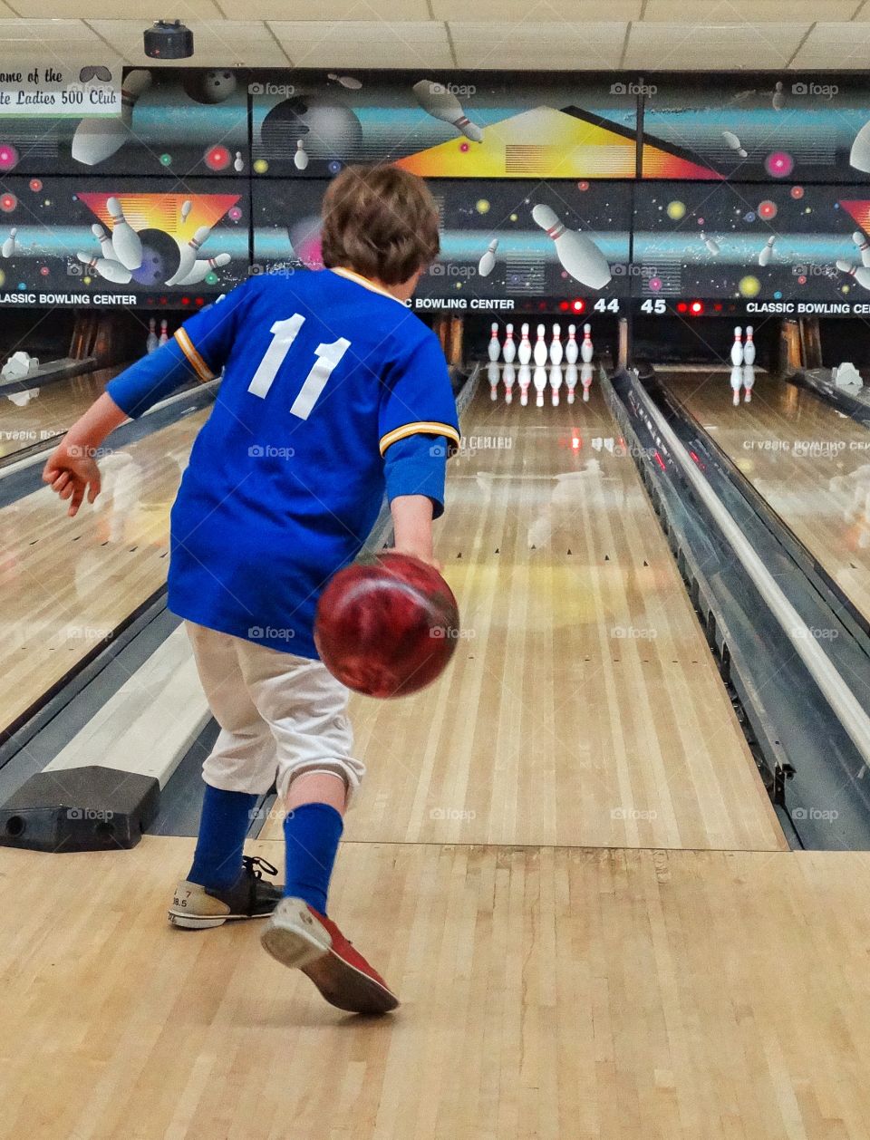 Young Boy Going Bowling. Young Boy Pitching A Bowling Ball At An American Bowling Lane
