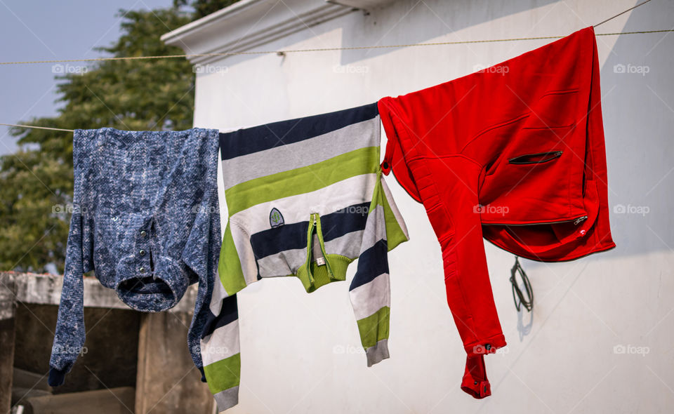 Sweater and jackets drying on a rope in sun