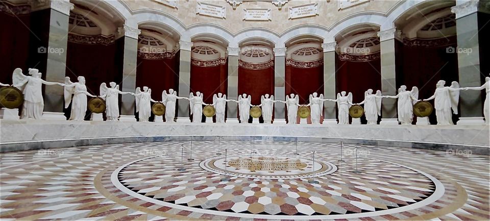 This is “Liberation Hall” in “Kelheim”, Bavaria on the “Danube”. Built in Greco-Roman classical style this colossal circular hall has larger than life angels with outstretched arms all around and a multifaceted tiled floor. 2024. Hypnotic Productions
