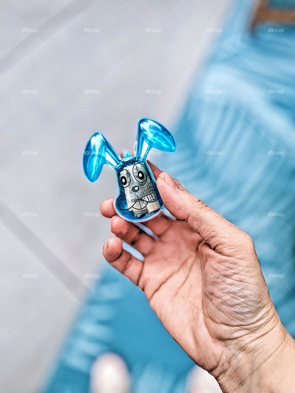 Woman’s hand holding a rabbit shaped Easter egg, blue rabbit shaped Easter egg filled with money, woman’s hand holding egg, finding the Easter eggs, on the hunt for Easter eggs, adult Easter egg hunt