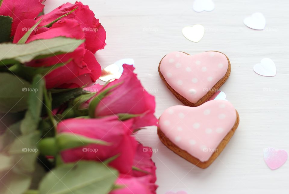 two gingerbread hearts and a riot of red roses on the table