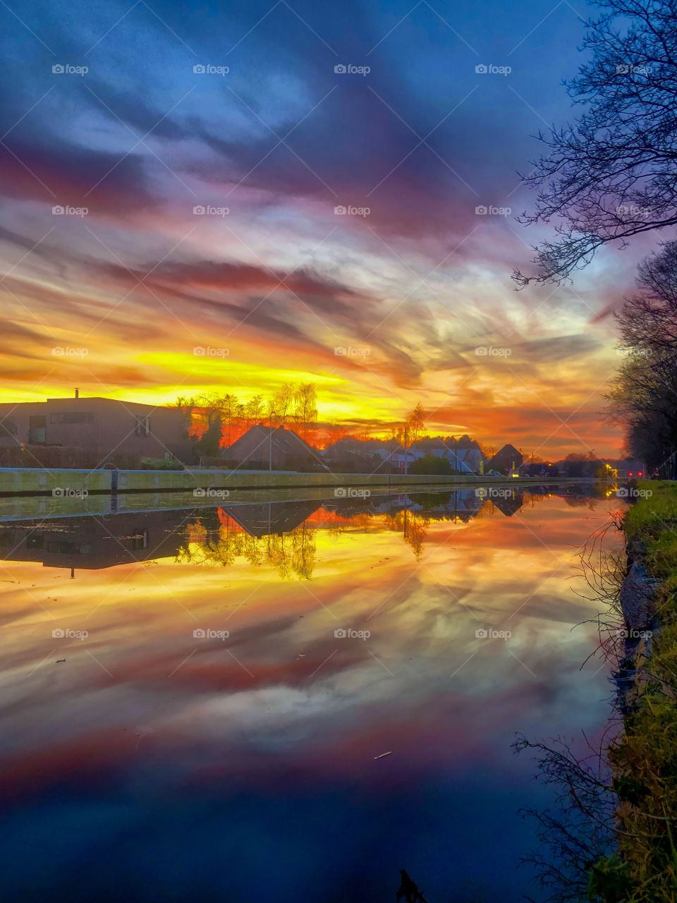 Dramatic and colorful sunset over the river with the gold, yellow, orange, red, purple and blue colors of the sky and the Clouds reflected in the water