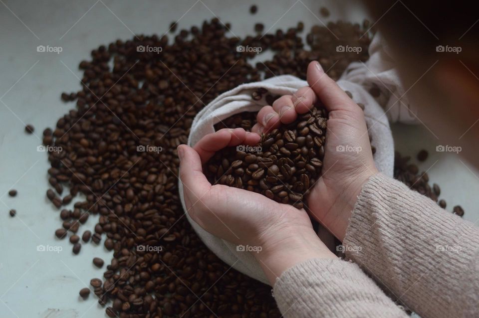 coffee beans in the hands in the shape of heart.