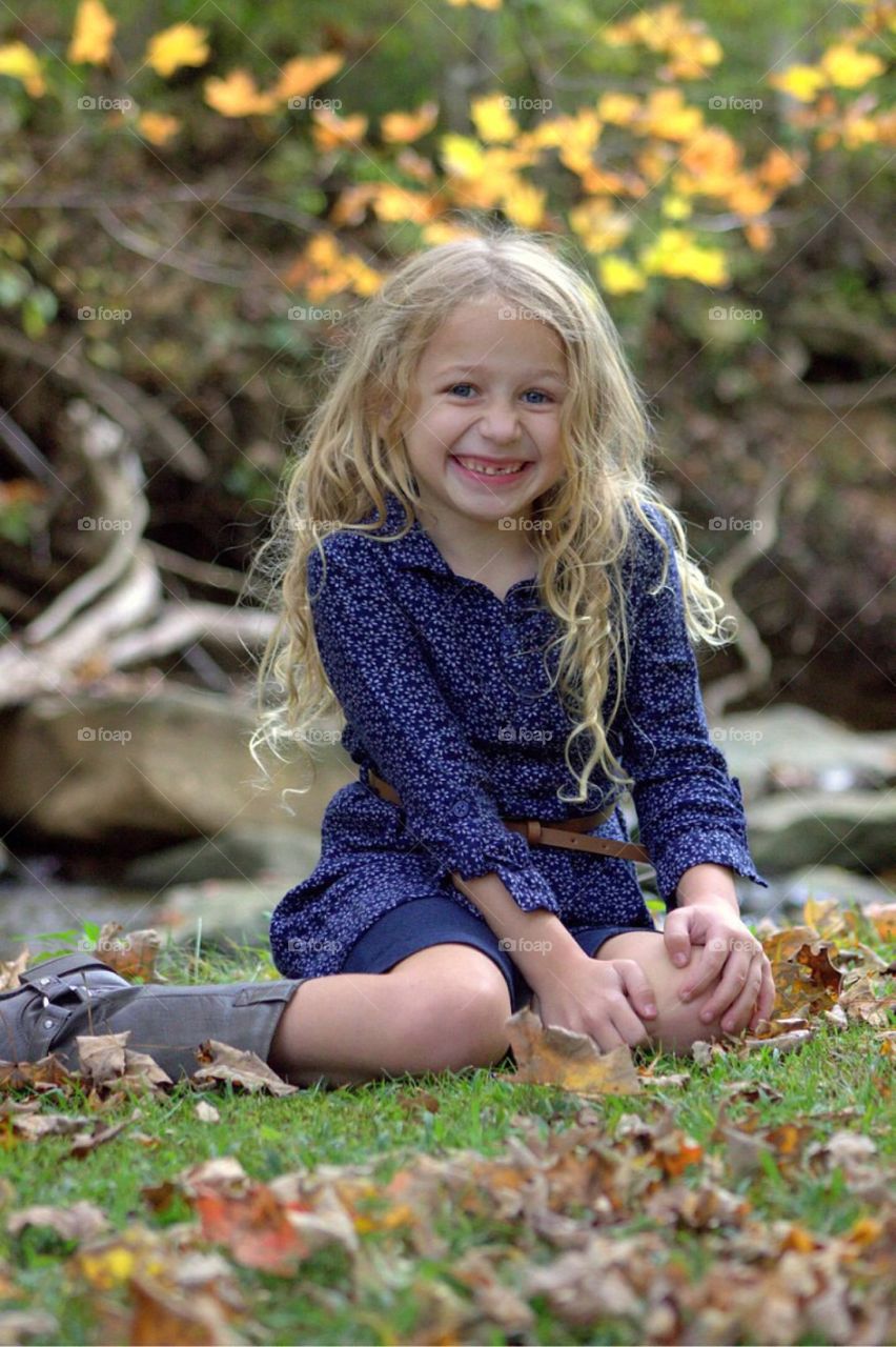 Cute smiling girl sitting at park during autumn