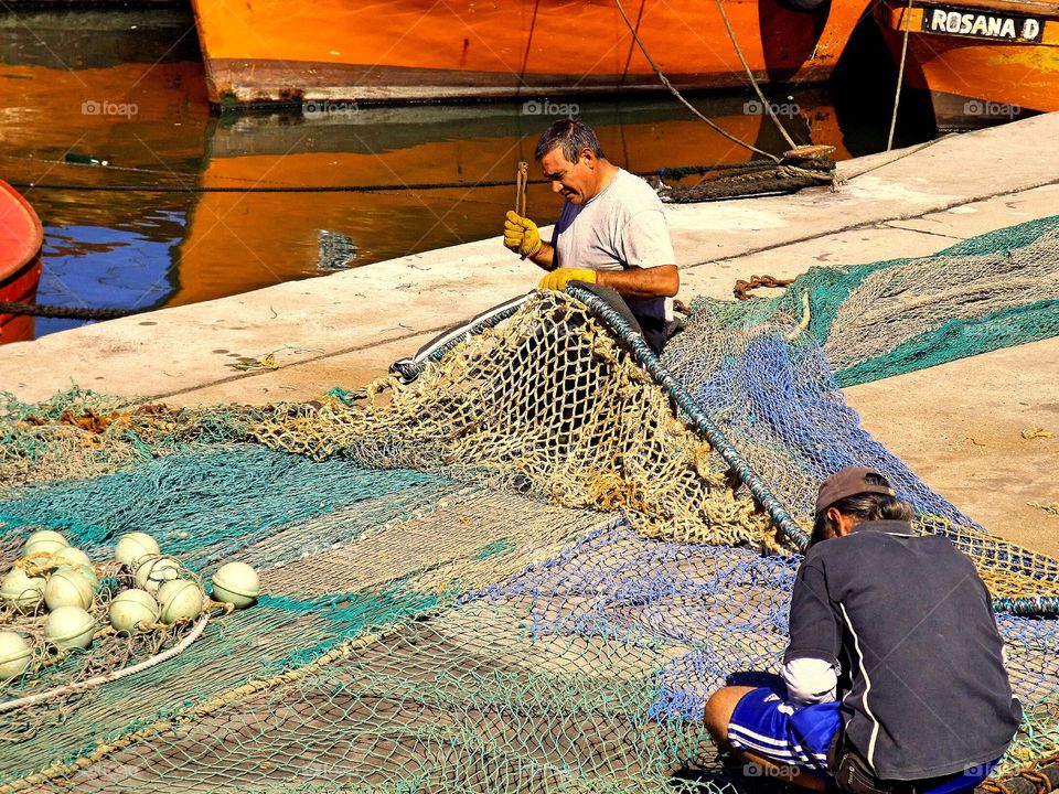 Net sewing at the fishing port. Fishers working 