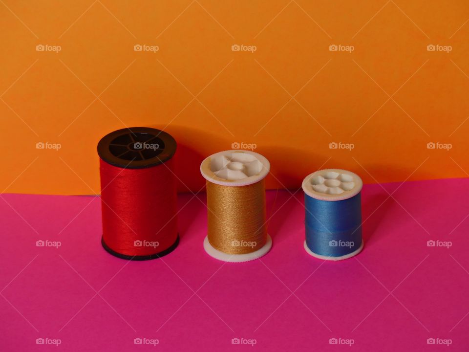 Three spools of thread - The Power of Threes - Everything that comes in threes is perfect, or, every set of three is complete, conveys the same idea as the rule of three. Displayed on Bright, colorful backgrounds. 