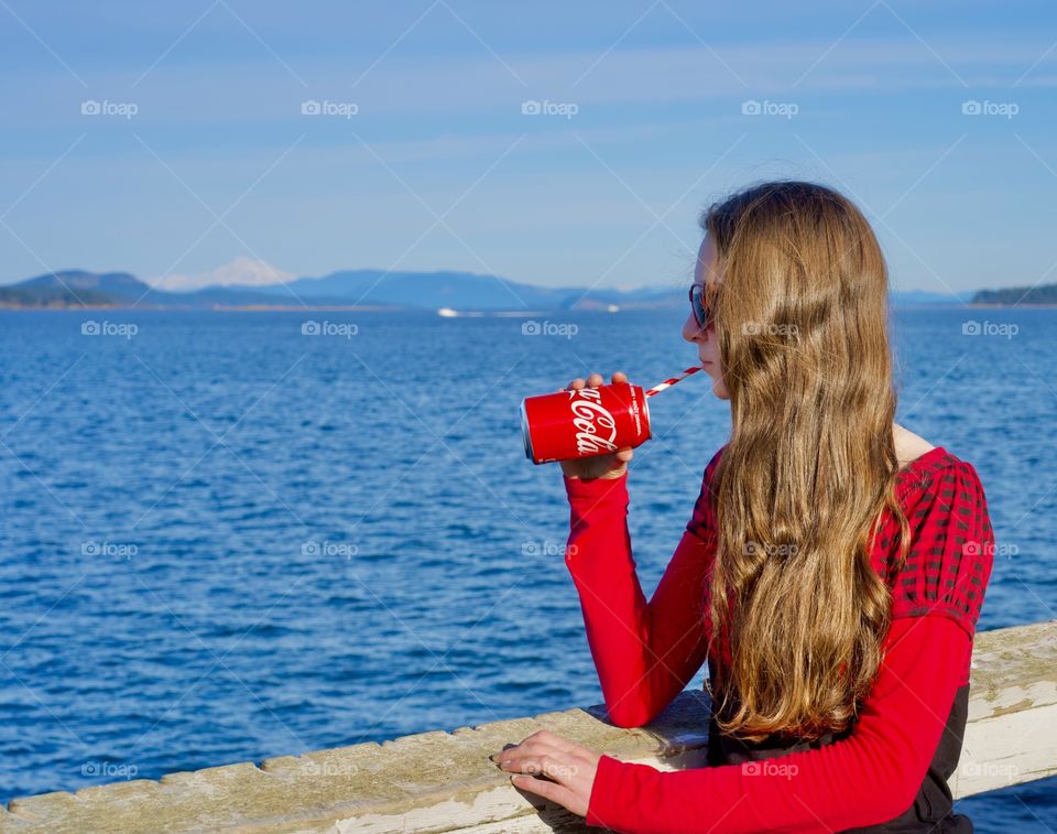 Girl drinking cola on an scenic ocean walkway 