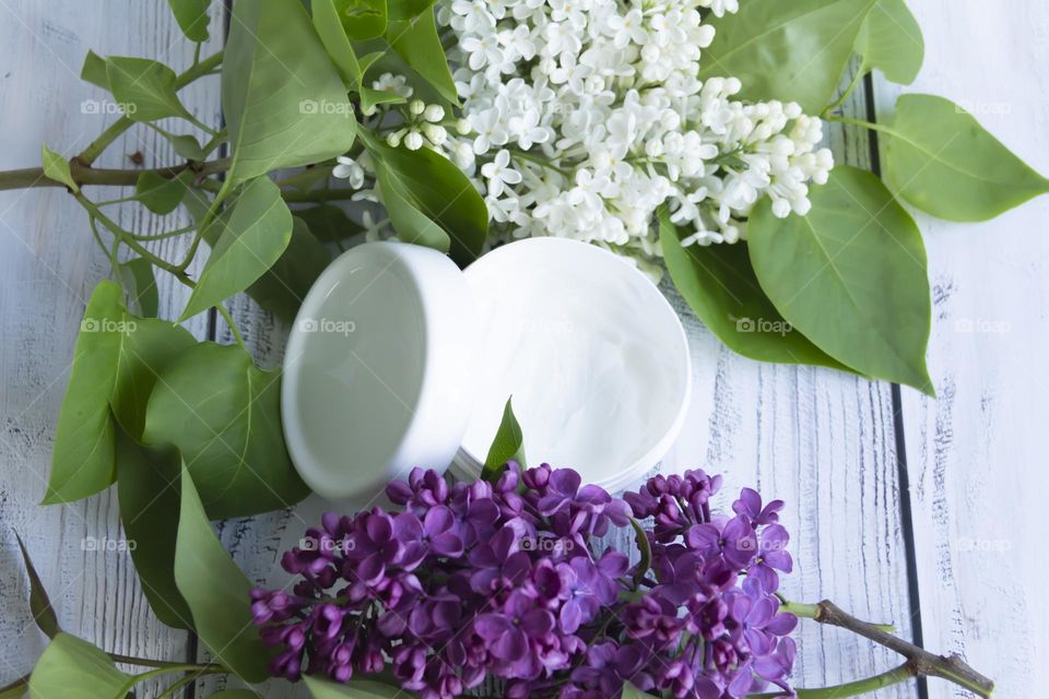 Spring, white fragrant lilac with green leaves.  and jars with cosmetic cream and product.