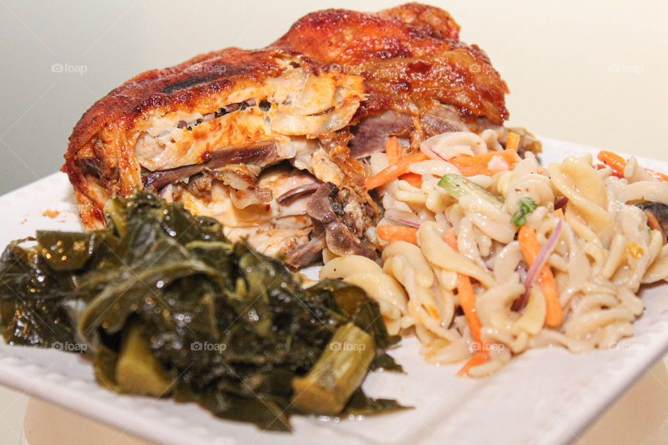 A cornish hen dinner with all natural pasta salad and fresh collard and kale greens