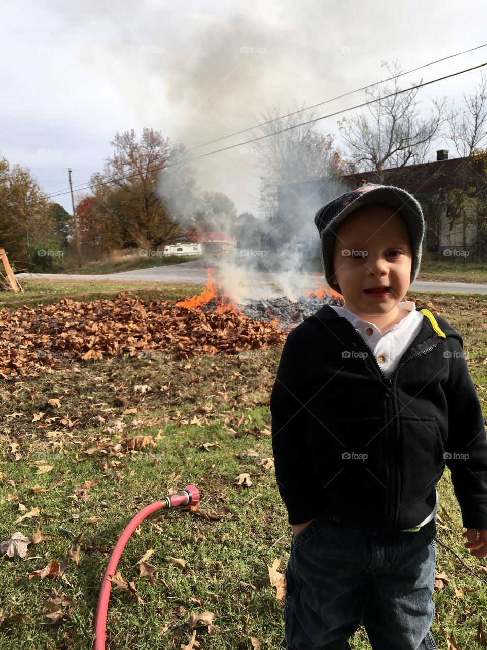Little boy standing in front of fire