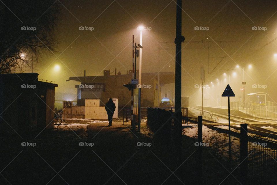 A lonely silhouette of a man at a railway station at night
