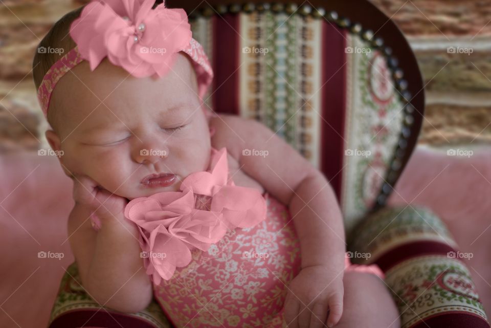 Newborn baby girl posing in a doll chair 