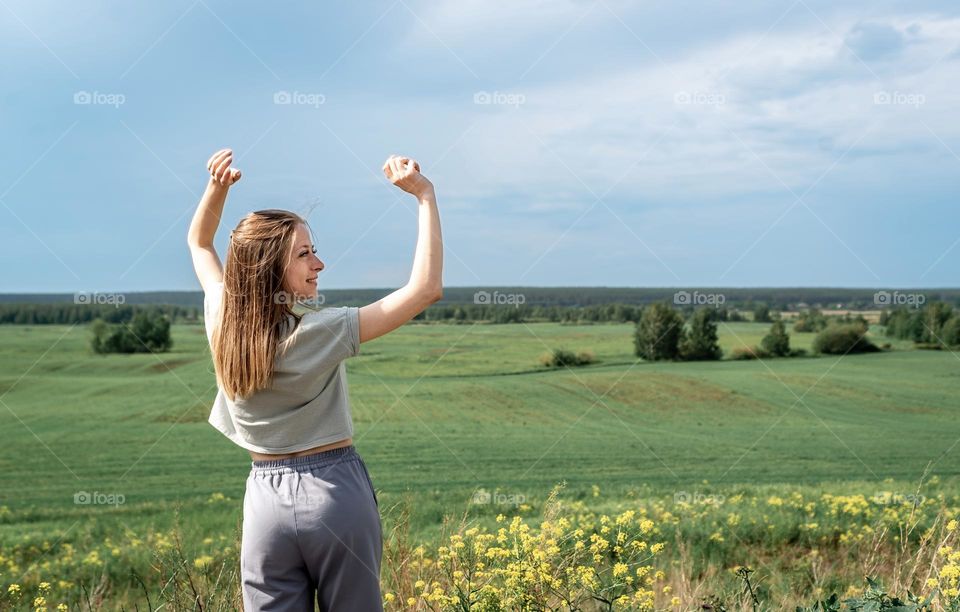 A young girl in a tracksuit in a field, the concept of freedom? raised her hands up