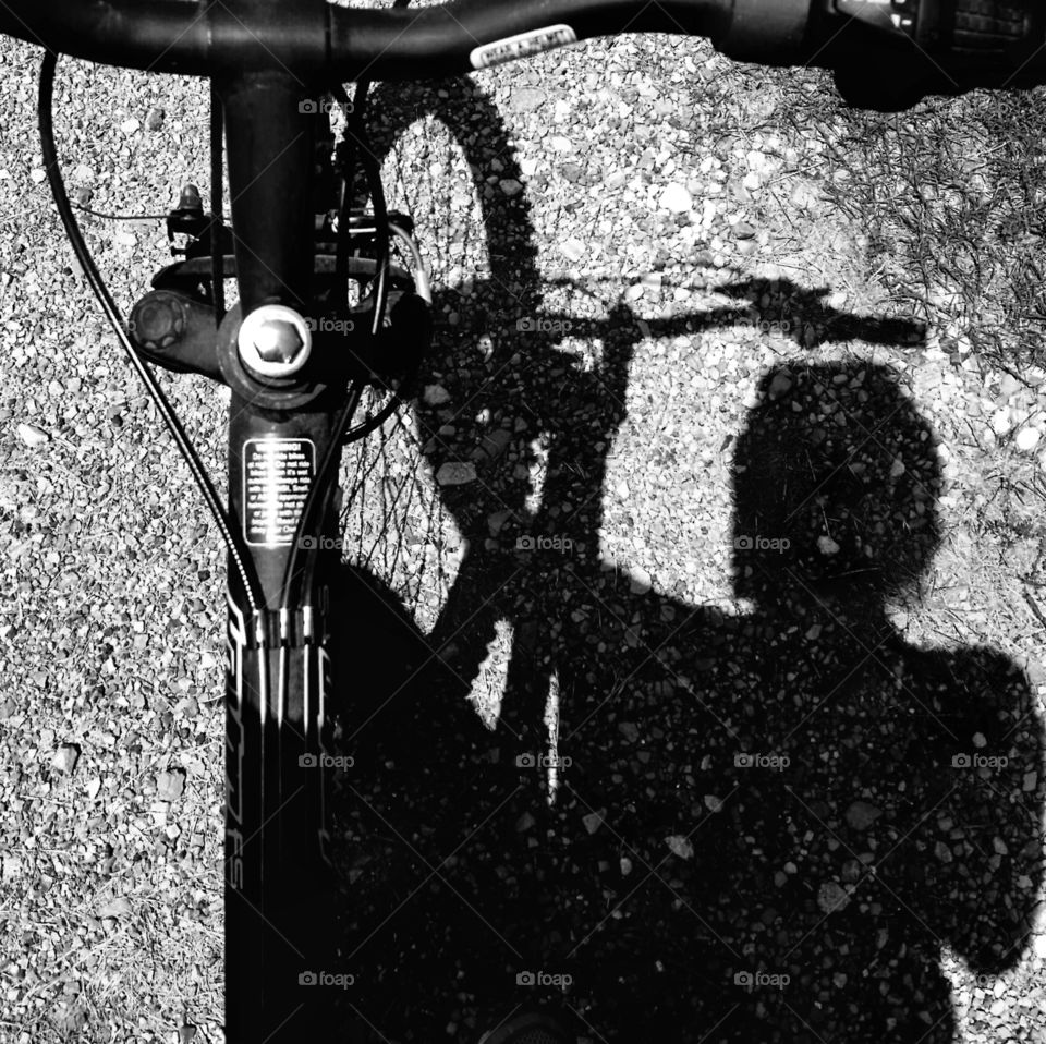 A woman and her bike in shadow in black and white