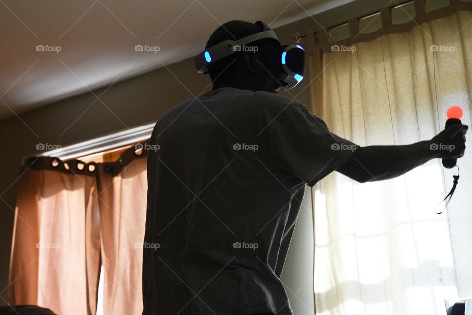 A young man engages in a session of virtual reality gaming in the living room of his home.