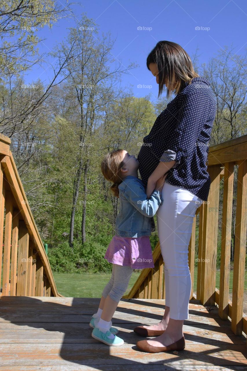 Little girl leaning against her pregnant mom