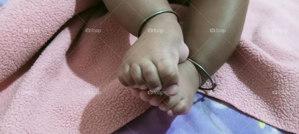 This photo of legs of little baby girl. Playing baby girl (kids) with herself. little baby girl moving her hands and legs and talking own and playing itself. Wondering moment captured in photo.