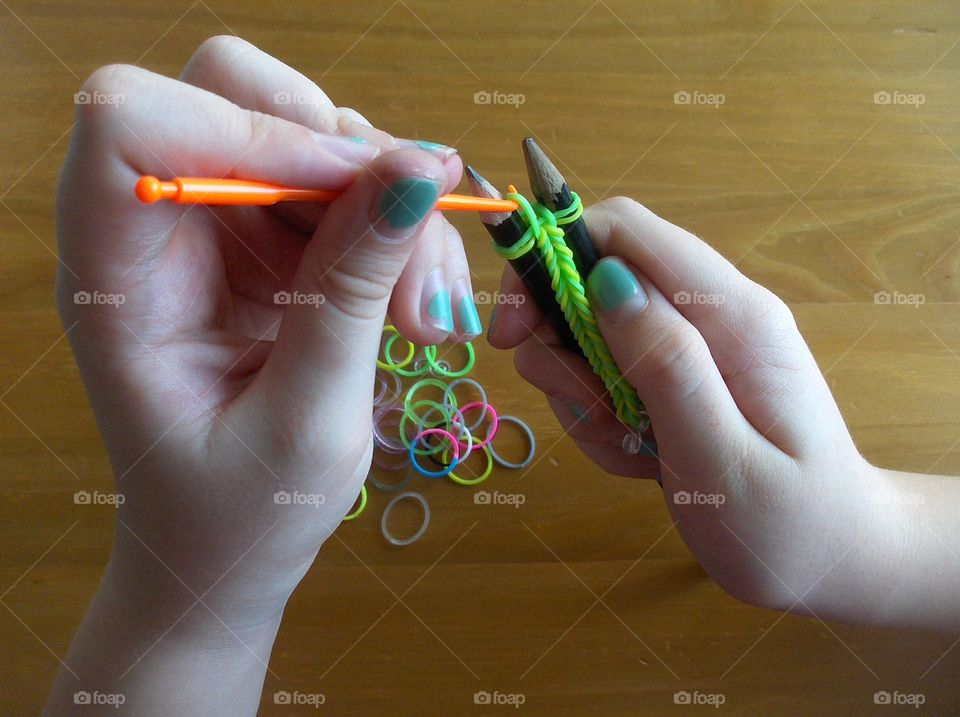 closeup girl's hands making bracelet from rubber rings