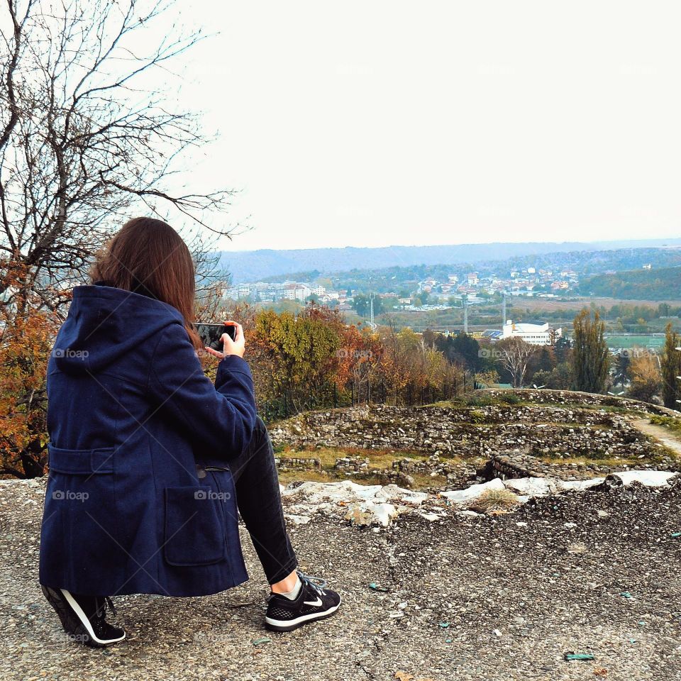 A woman taking a photo of a beautiful autumn landscape for Foap missions in Bulgaria