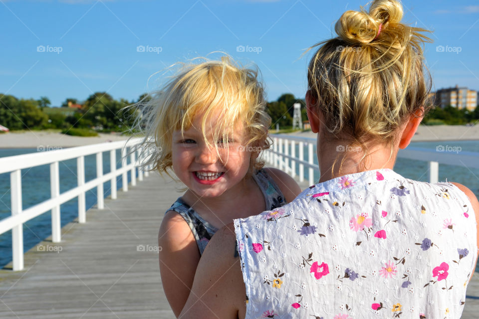 Rear view of a mother carrying her daughter on pier