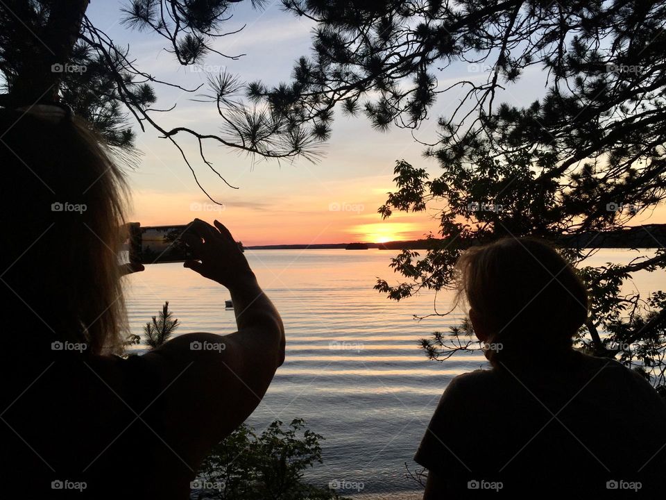 A photo of a woman taking a photo of a beautiful sunset.