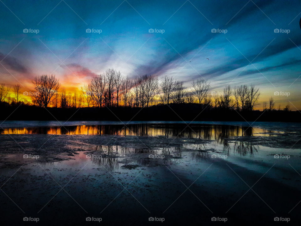 A colorful, early spring sunset reflected on a pond.