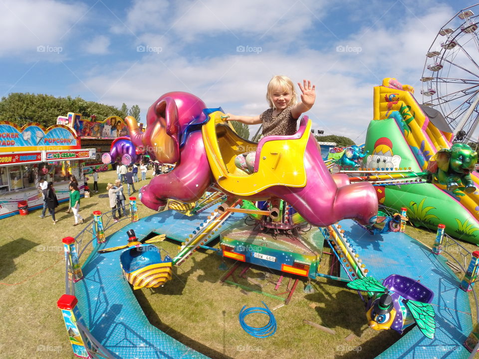 Four year old little swedish girl riding carousel at a local amusement park in Sweden.