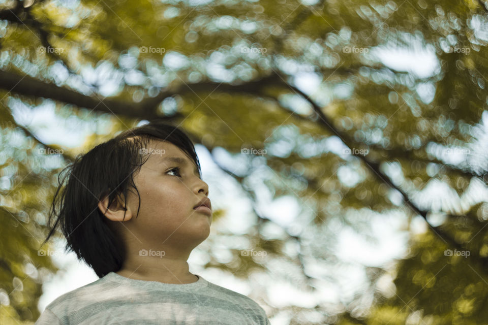 outdoor portrait of young eurasian boy on a blurry out of focus bokeh foliage background