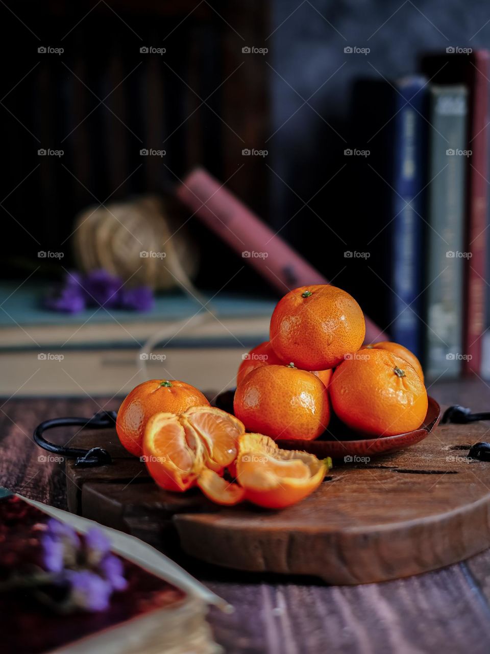 Tangerines, peeled tangerine and tangerine slices on wooden chopping board with rustic background.