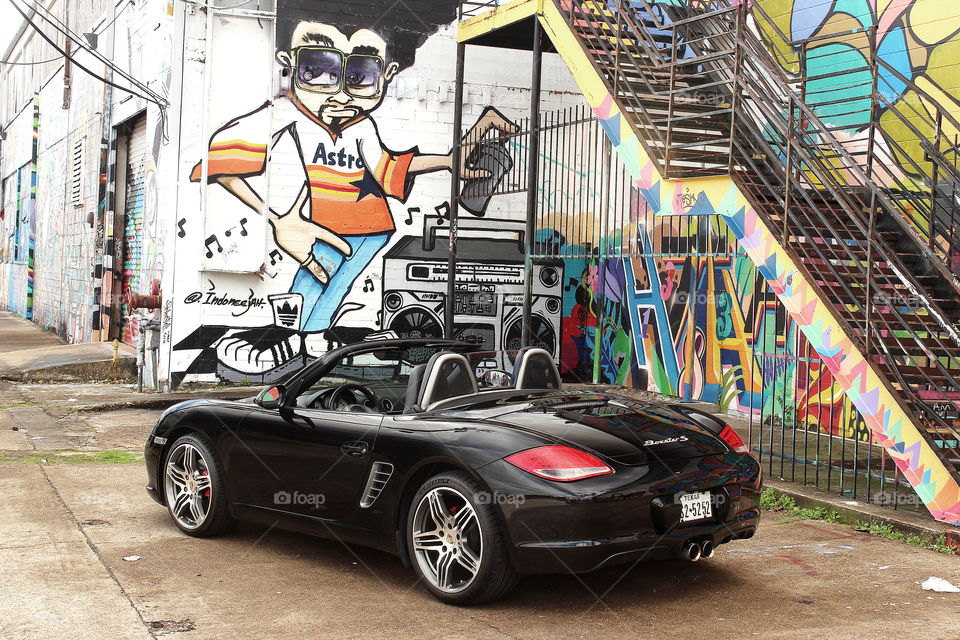 Black porsche convertible in city with graffiti wall