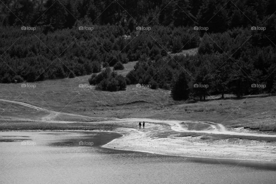 Two girls walking near lake, black and white landscape 