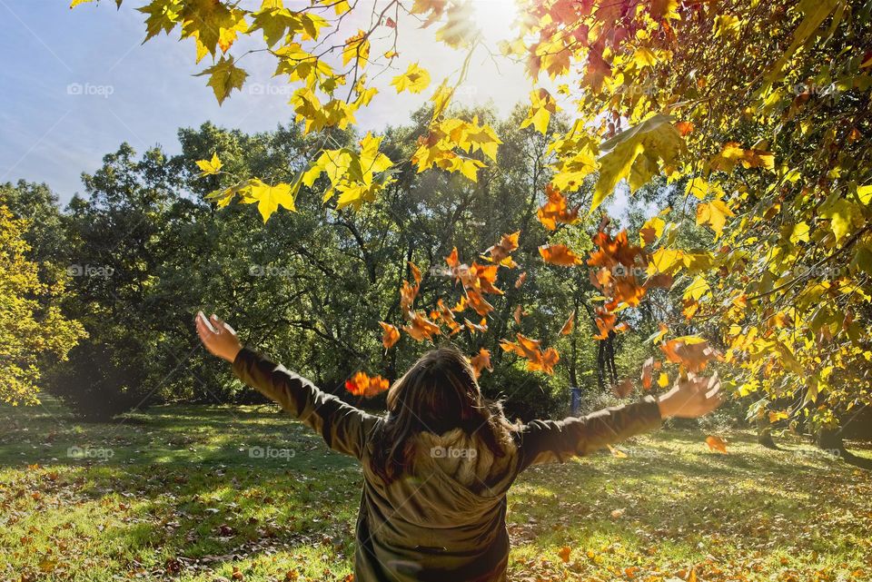 Teenage girl throws dry leaves in Autumn 