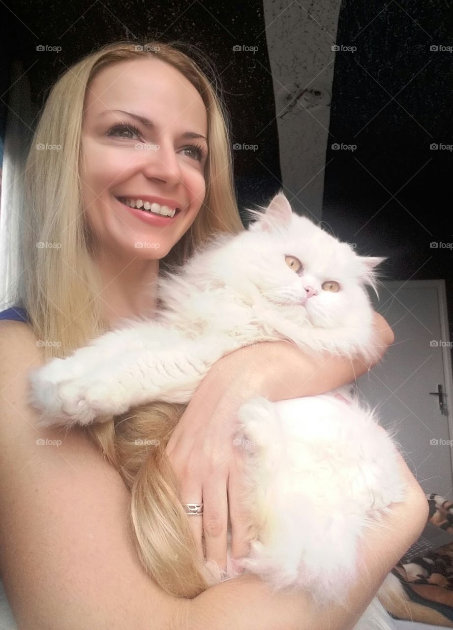 Happy young woman holding cute white cat