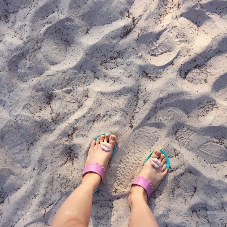 Selfie of woman feet wearing flip flops on a beach, vintage process