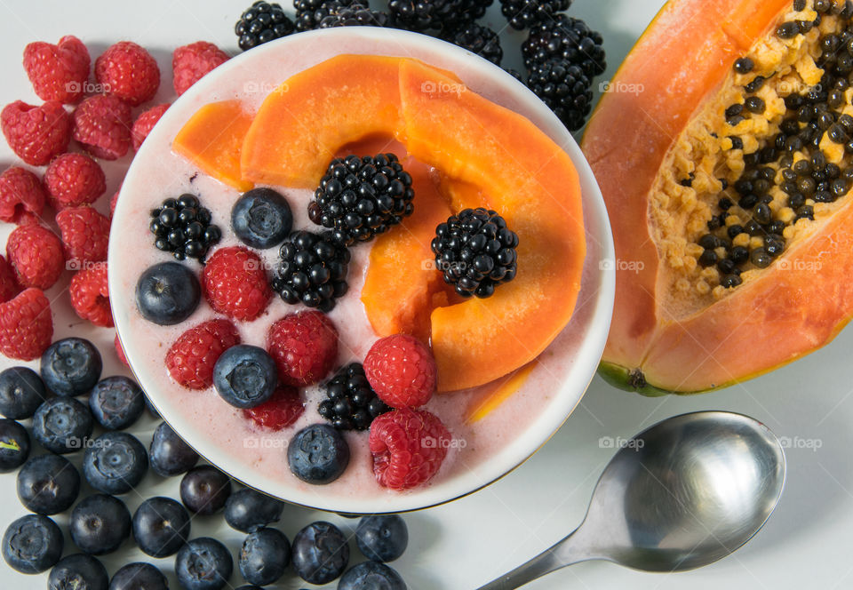 Closeup shot of yoghurt and fruit smoothie with berries and papaya