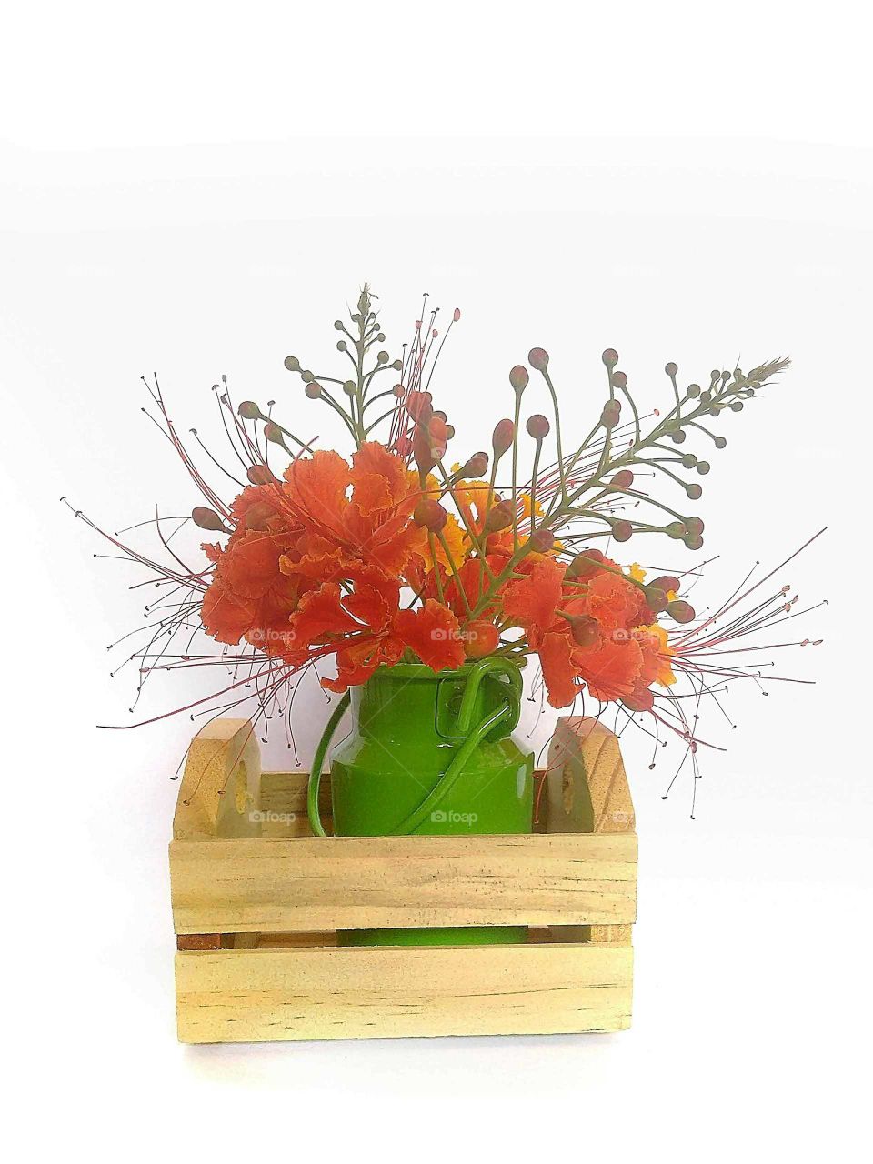 Ornamental composition of Poinciana flower in vase inside mini wooden crate.
