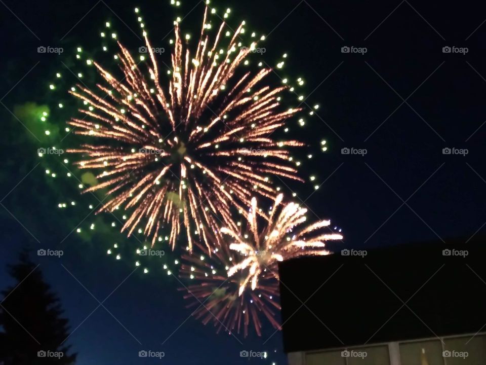 A large magnificent display of an exploding fireworks spewing a starlit image in white and pink glittering sparkles